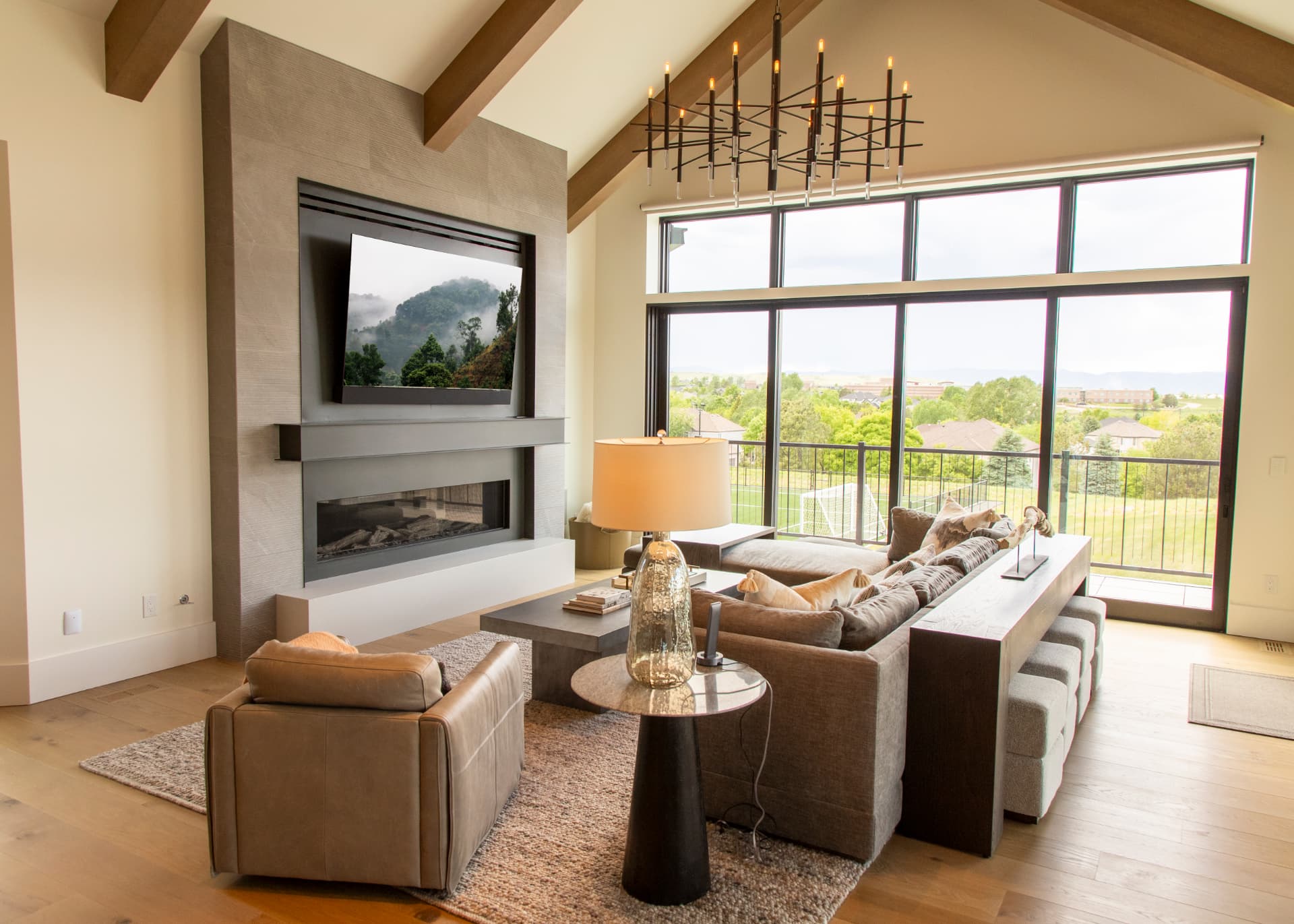 Vaulted great room with fireplace-mounted television, chandelier, and floor-to-ceiling windows