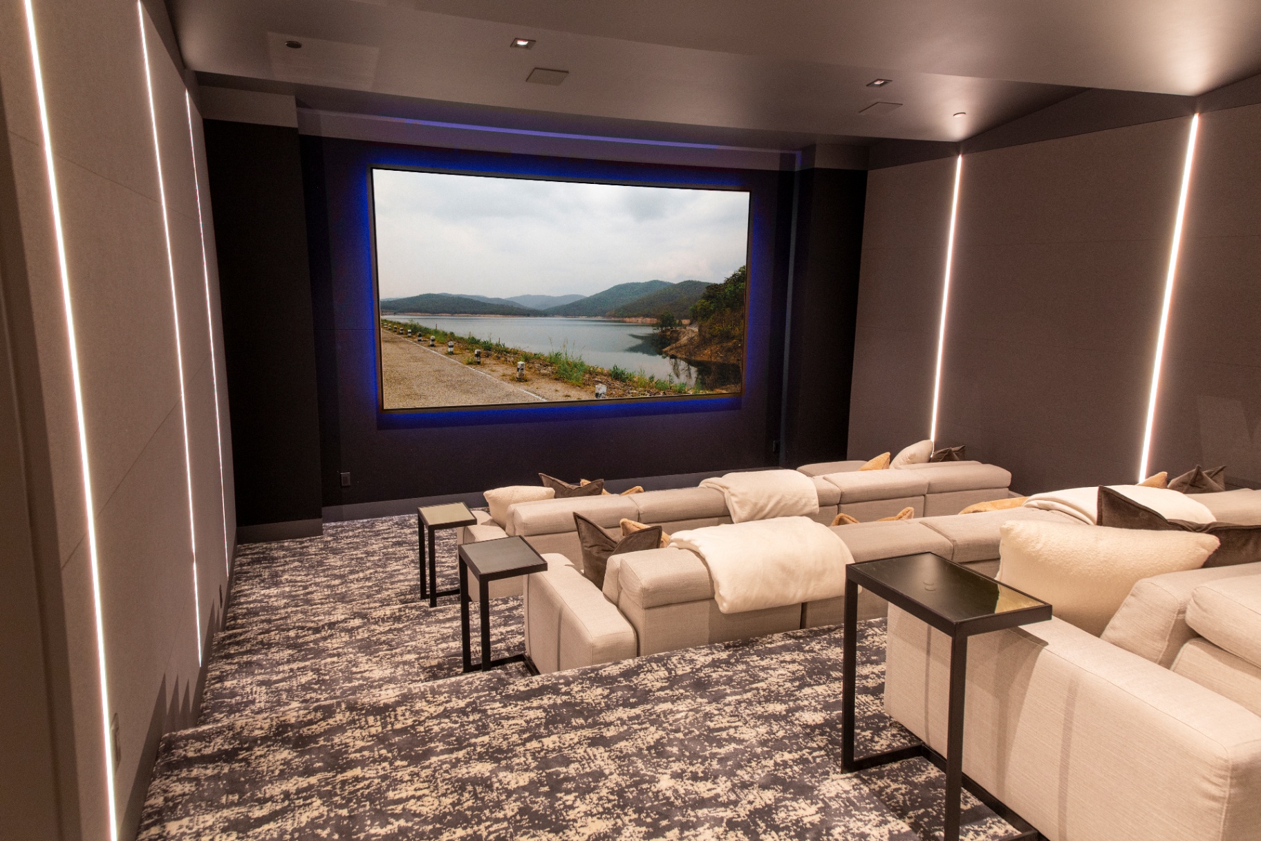 Wide-format home cinema with layered ambient lighting and plush seating