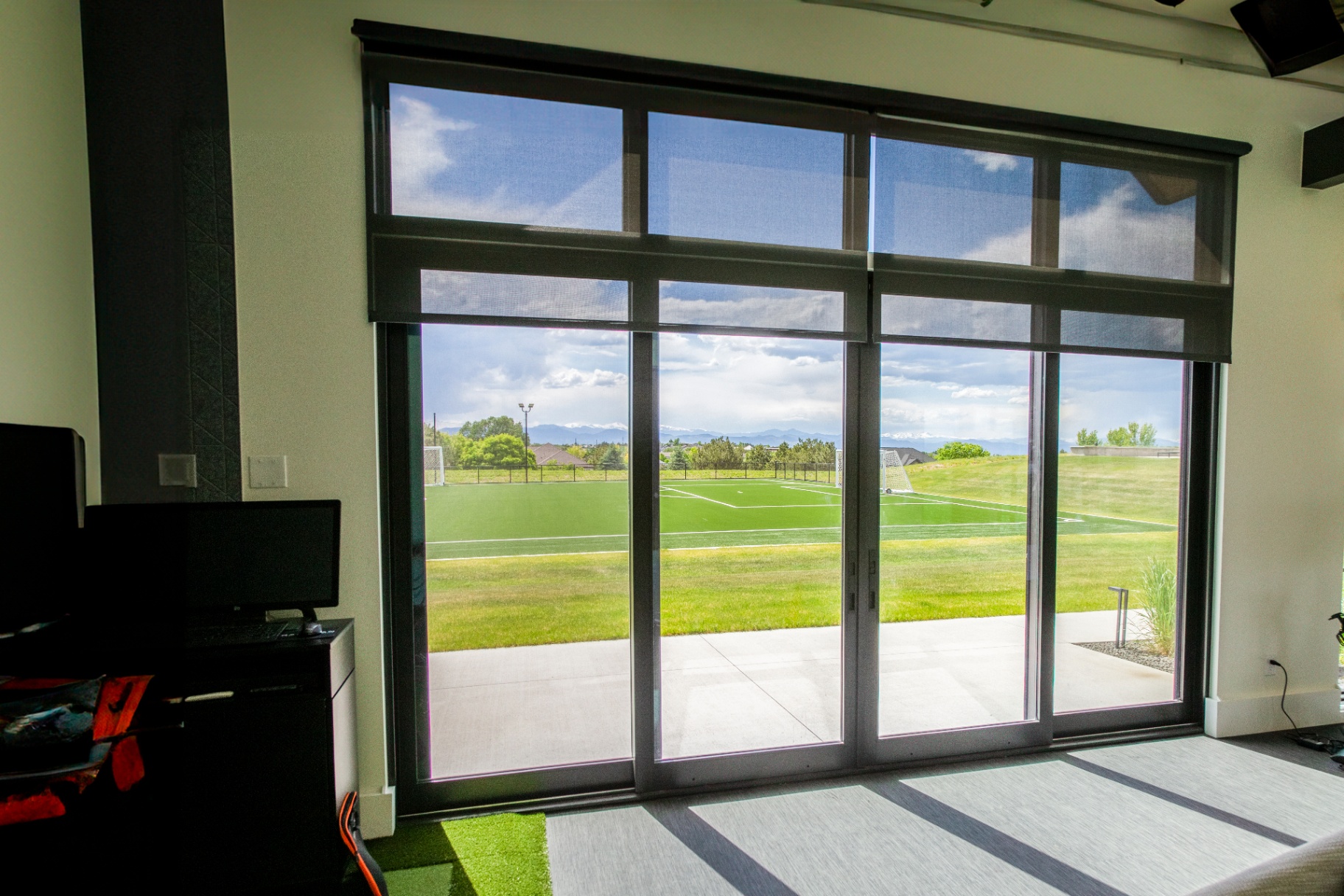 Motorized solar shades overlooking a Lone Tree soccer field and mountain view