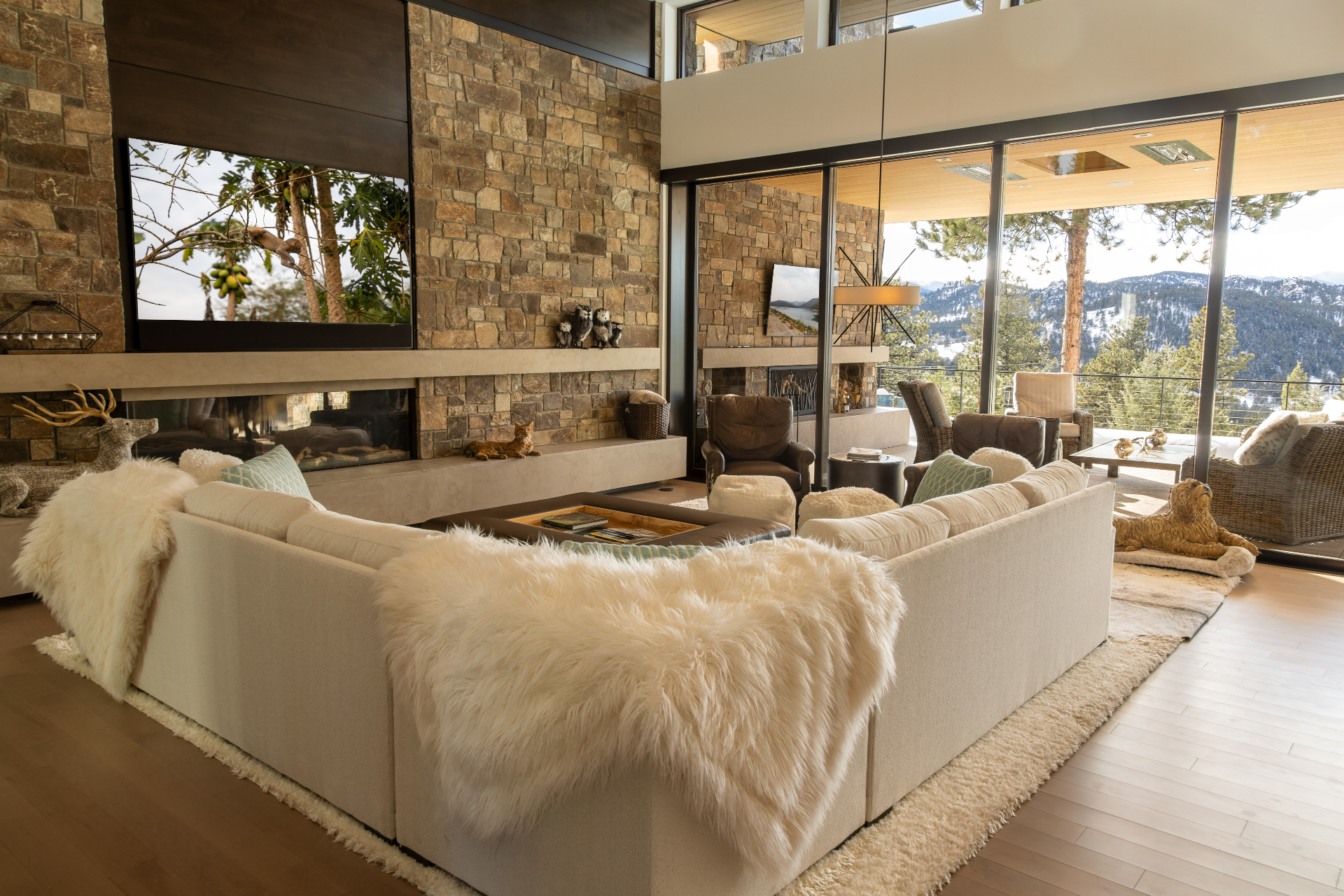 Living room with integrated television over a stone fireplace and mountain views