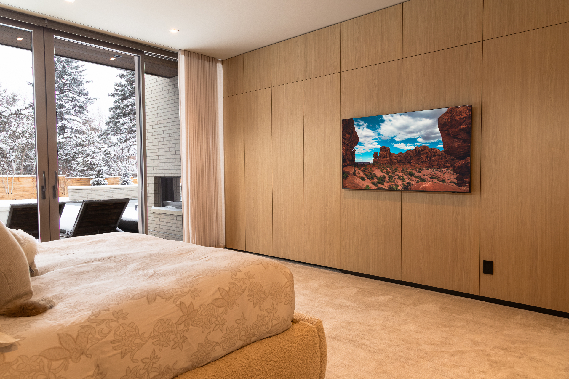 Primary bedroom with wall-integrated television and motorized drapery