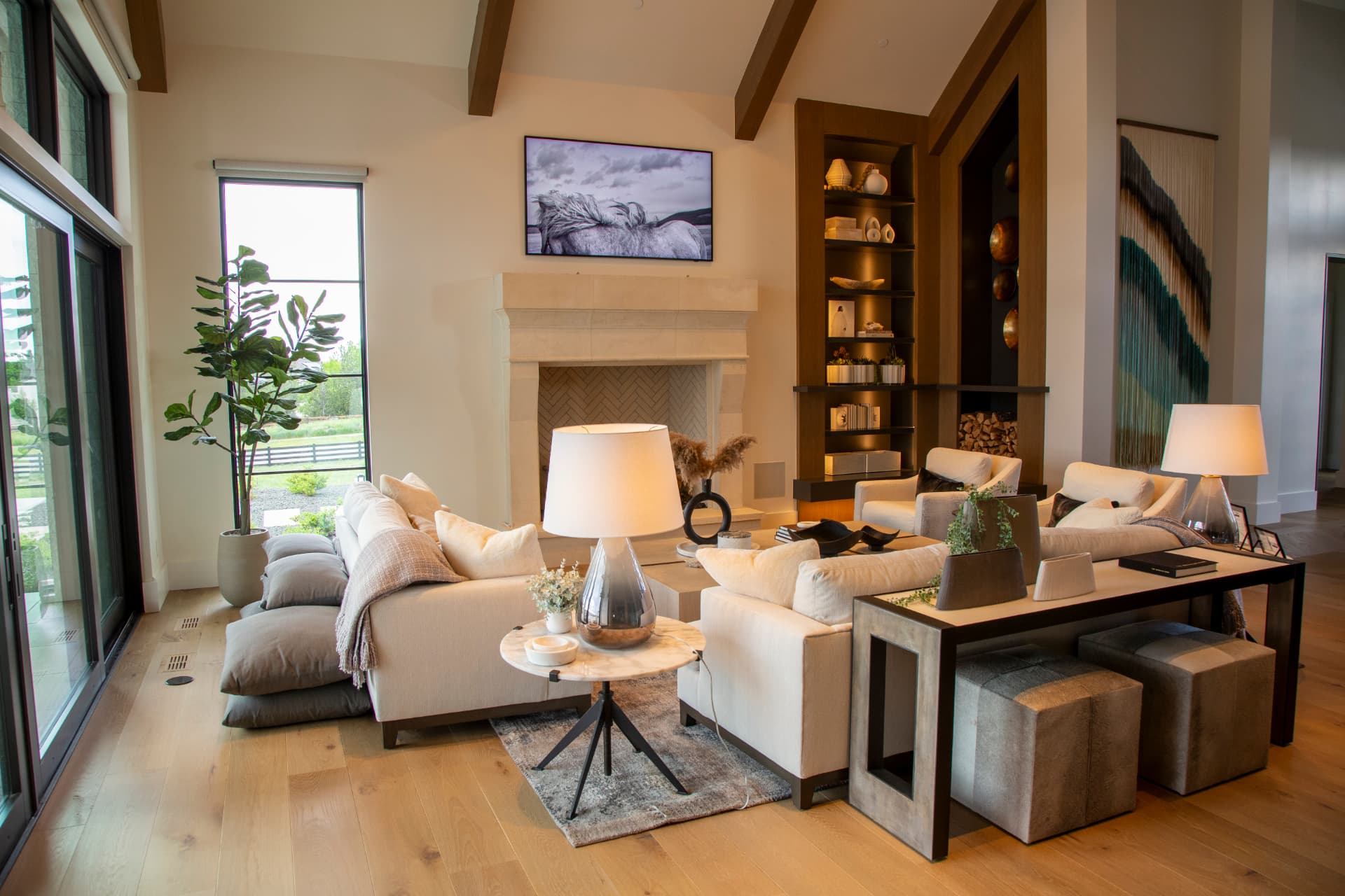 Great room with an art-mode television above a stone fireplace and mountain views