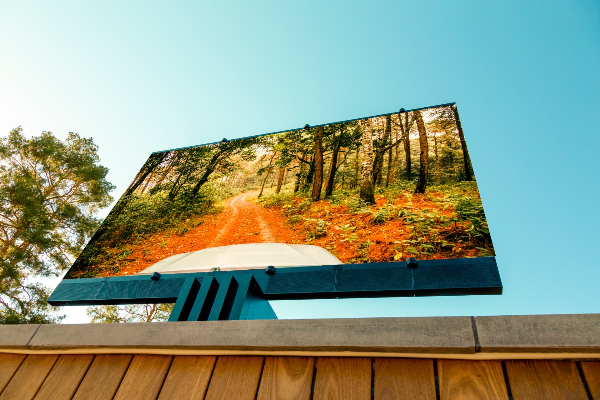 Weather-rated outdoor television with integrated soundbar mounted above a deck