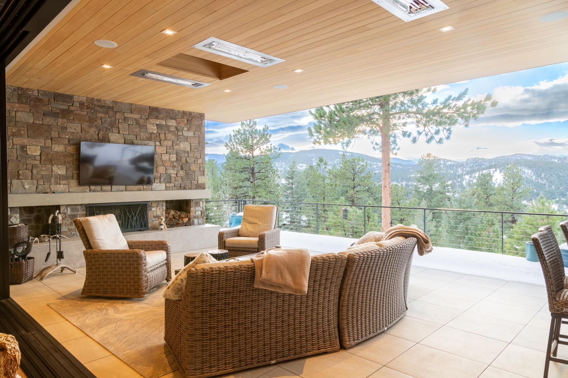 Covered outdoor patio with fireplace, television, and Colorado mountain views