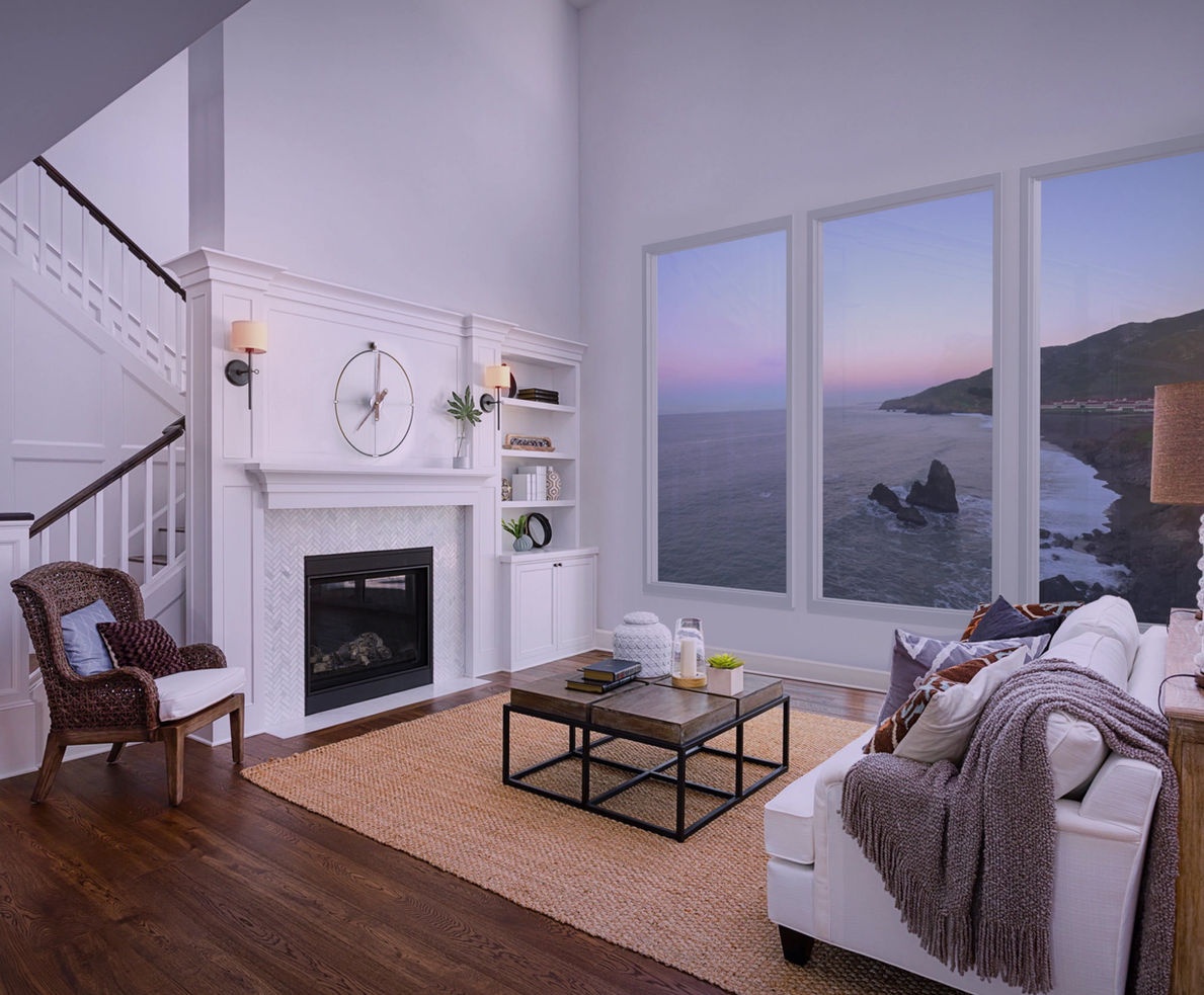 Living room with digital windows showing a coastal sunset view